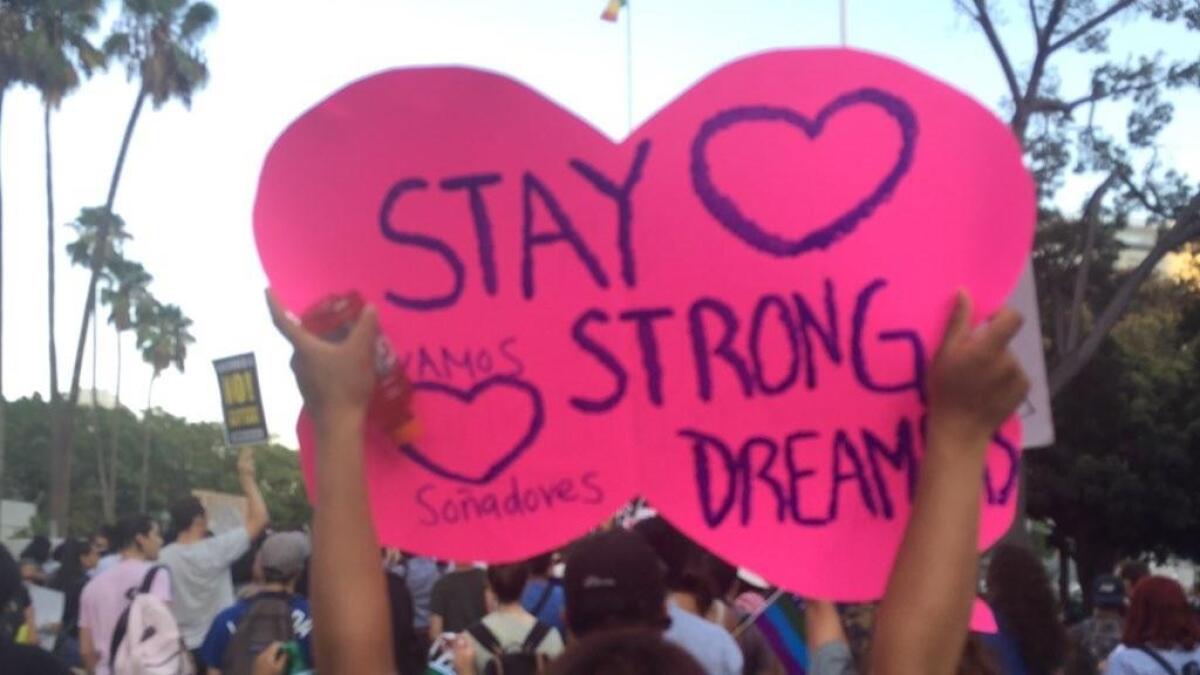 Zuleyma Chazari, a DACA recipient and USC student, hoists a sign outside City Hall.