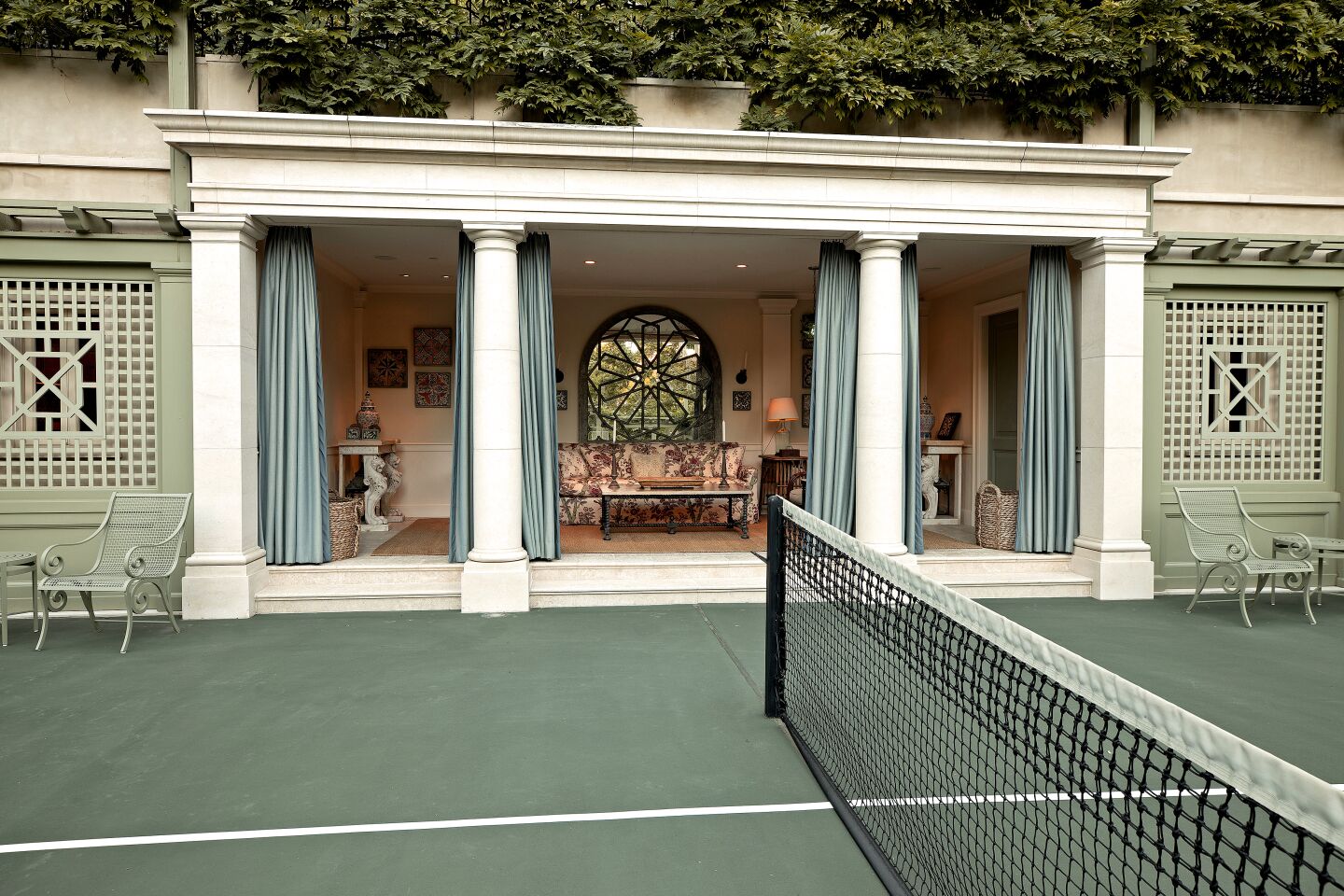 Tennis court with an open furnished room in the background.