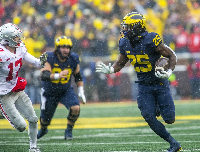 Michigan running back Hassan Haskins (25) rushes as Ohio State safety Bryson Shaw (17) chases in the fourth quarter of an NCAA college football game in Ann Arbor, Mich., Saturday, Nov. 27, 2021. (AP Photo/Tony Ding)