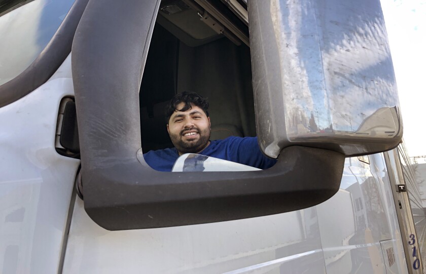 Adeel Nadeem sonríe desde el interior de la ventana del conductor de un camión