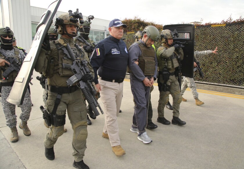 In this photo released by the Colombian Presidential Press Office, police escort Dairo Antonio Usuga, center, also known as "Otoniel," leader of the violent Clan del Golfo cartel prior to his extradition to the U.S., at a military airport in Bogota, Colombia, Wednesday, May 4, 2022. (Colombian presidential press office via AP)