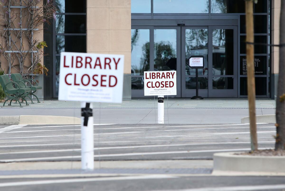 Signs outside the Newport Beach Central Library on Monday announce its closure due to the coronavirus outbreak.