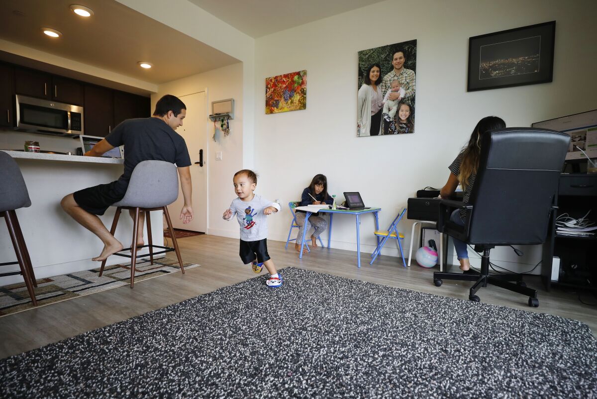 Lucas Fernandez, left, works from home while watching his children, Lucas Jr., 2, and Vienna, 7.