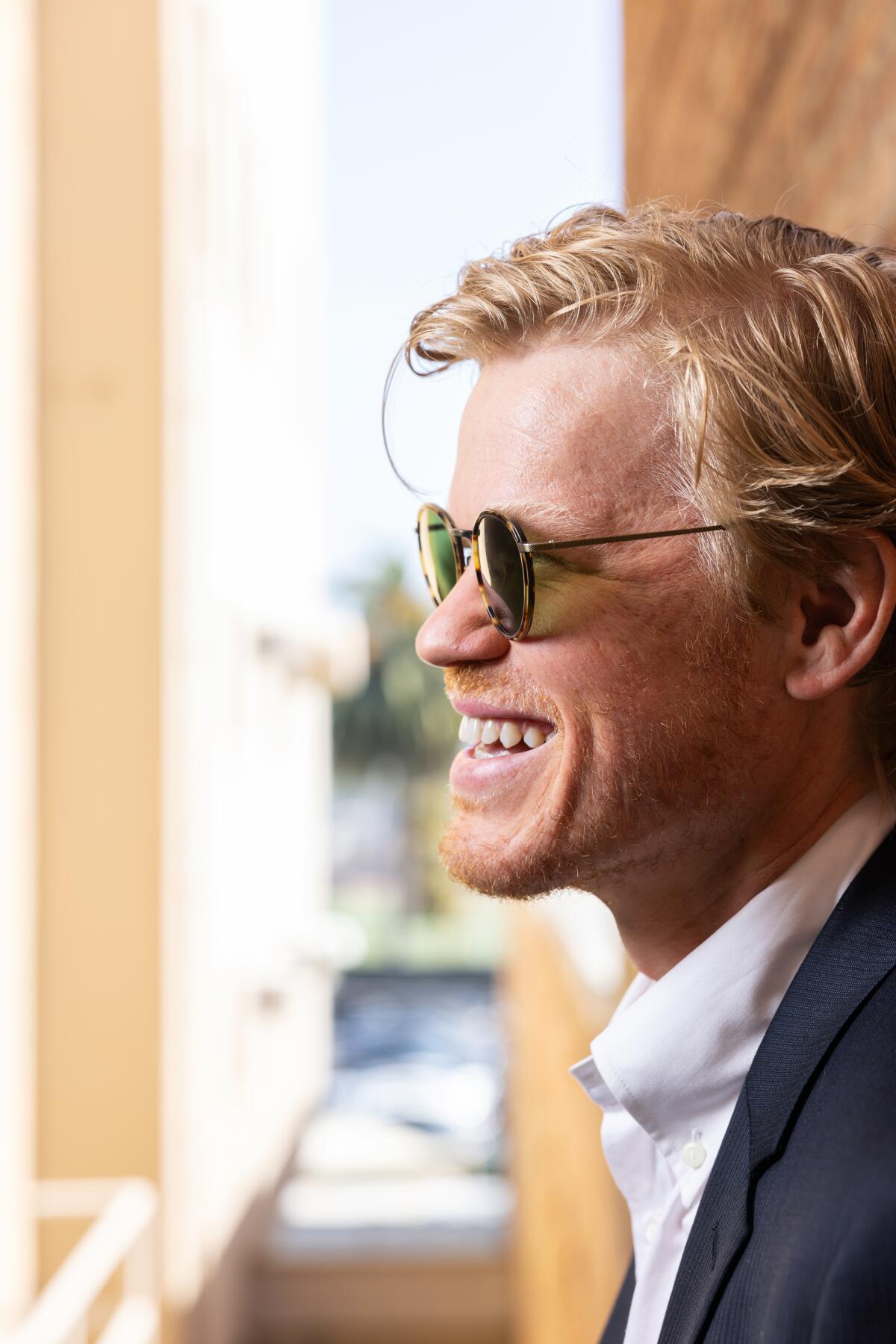 Jesse Plemons wearing sunglasses and a wide smile.