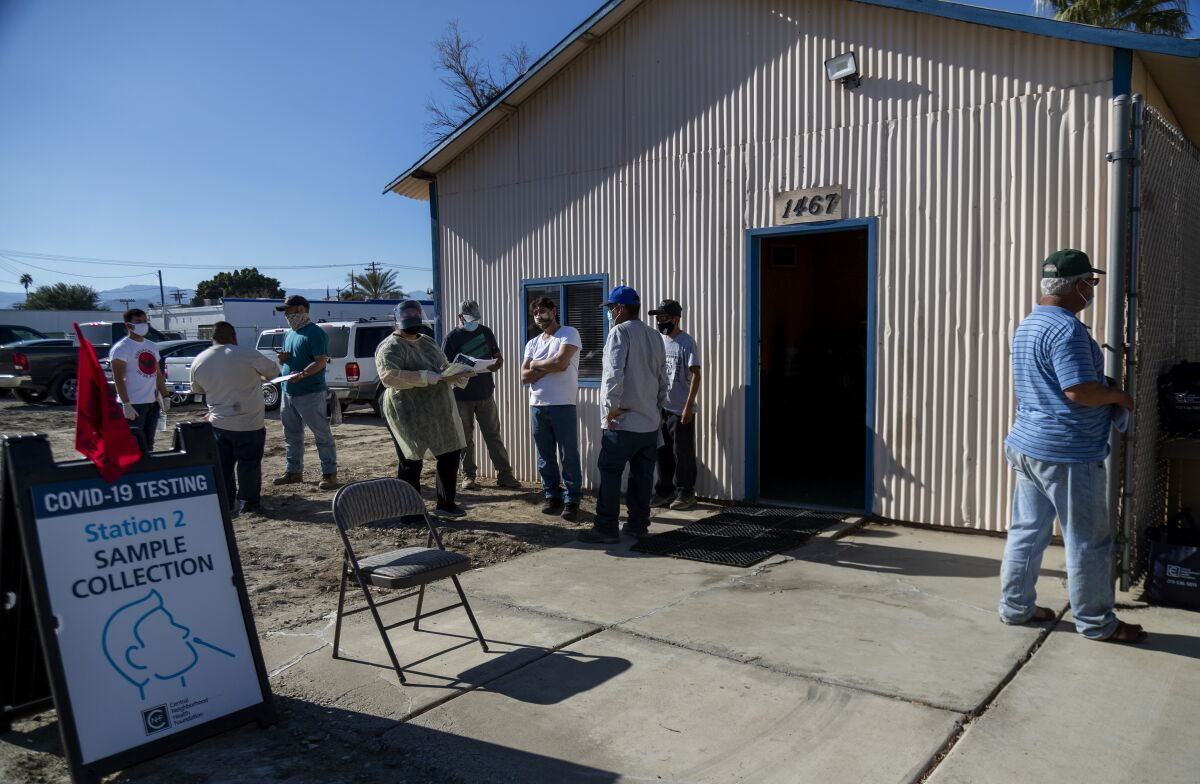 Farmworkers gather outside a building.