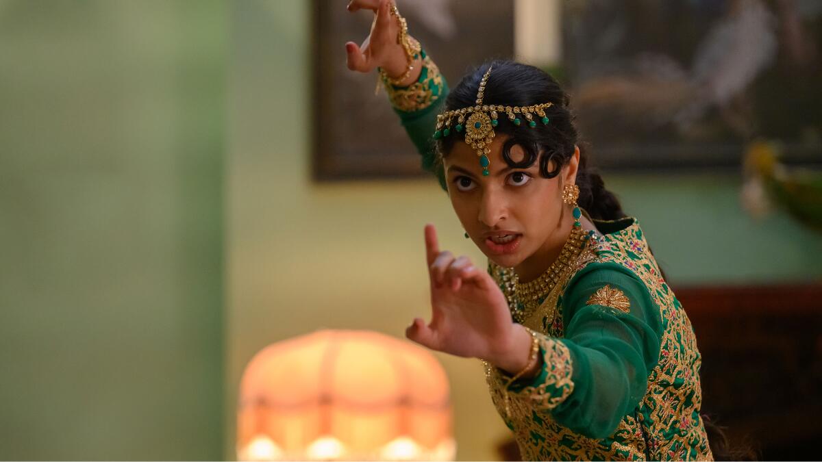A young woman in South Asian wardrobe practicing a martial arts pose.