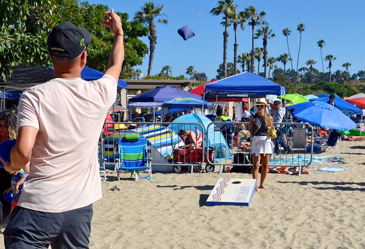 Mike Nguyen plays a game of cornhole with Diana Pham at Newport Dunes Tuesday.