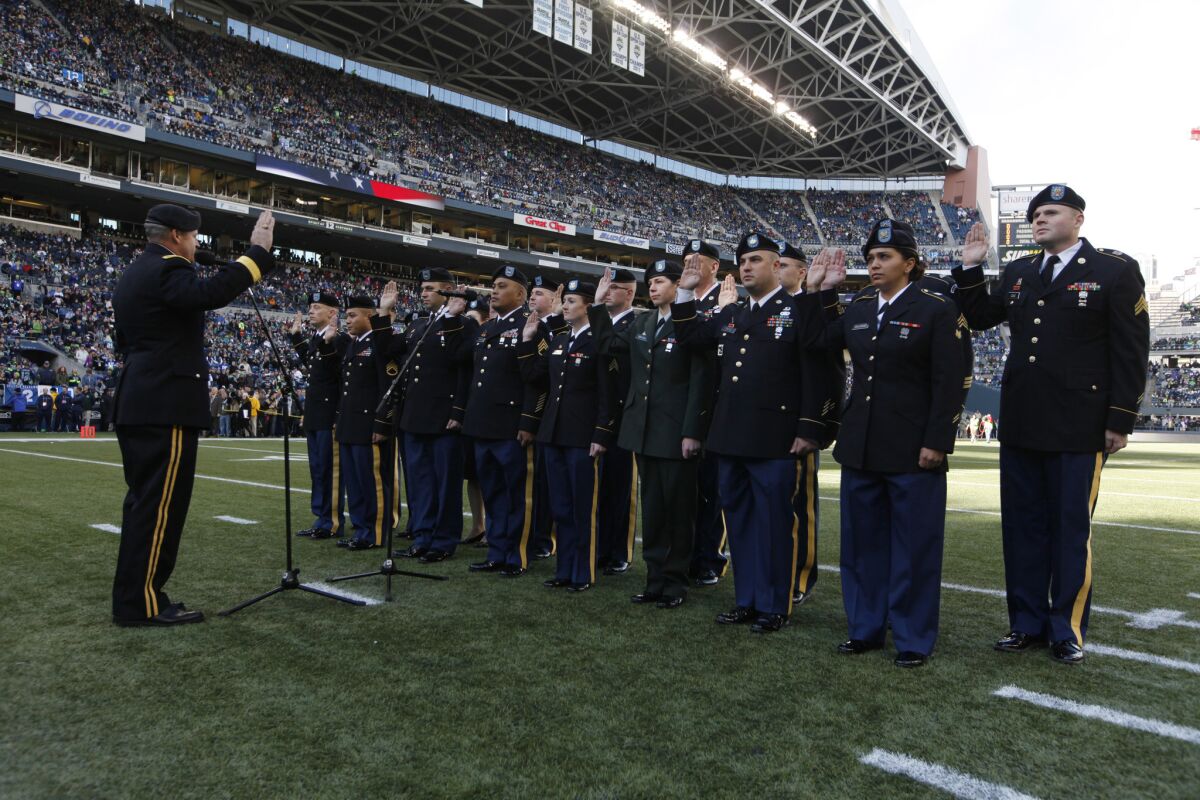 Washington National Guard members reenlist before an NFL game between the Seattle Seahawks and the Minnesota Vikings. Such events have come under criticism as "inappropriate and frivolous."