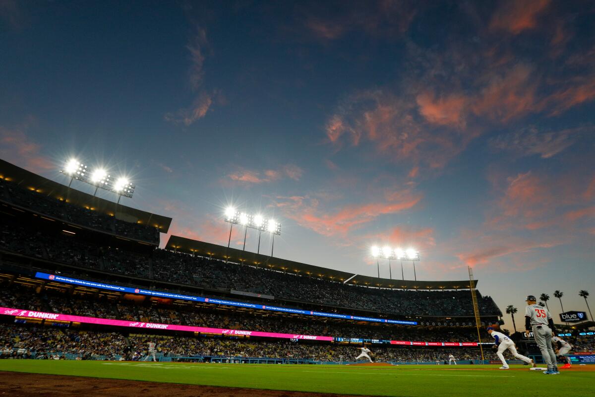 Pink clouds in a darkening sky at sunset over the lights of Dodger Stadium.