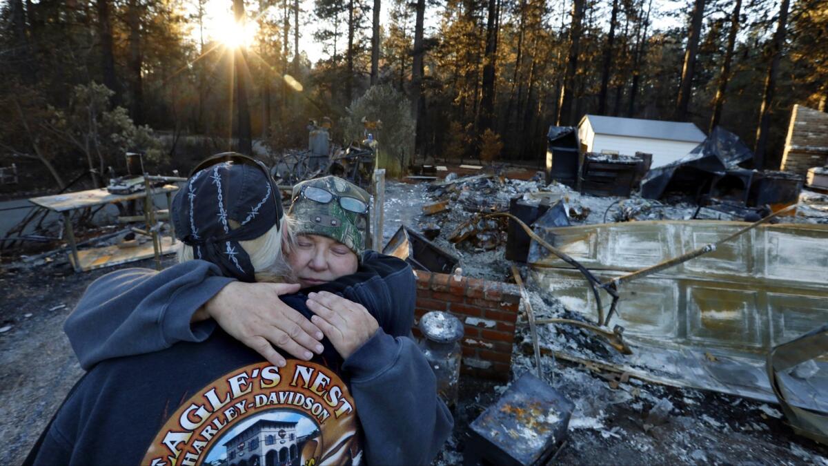 Kathy Tyler gets a hug from a friend Russ Vaugh after they work to recover what was left of the Tyler home. Kathy and her late husband, Charles, had lived in the area since 2002.