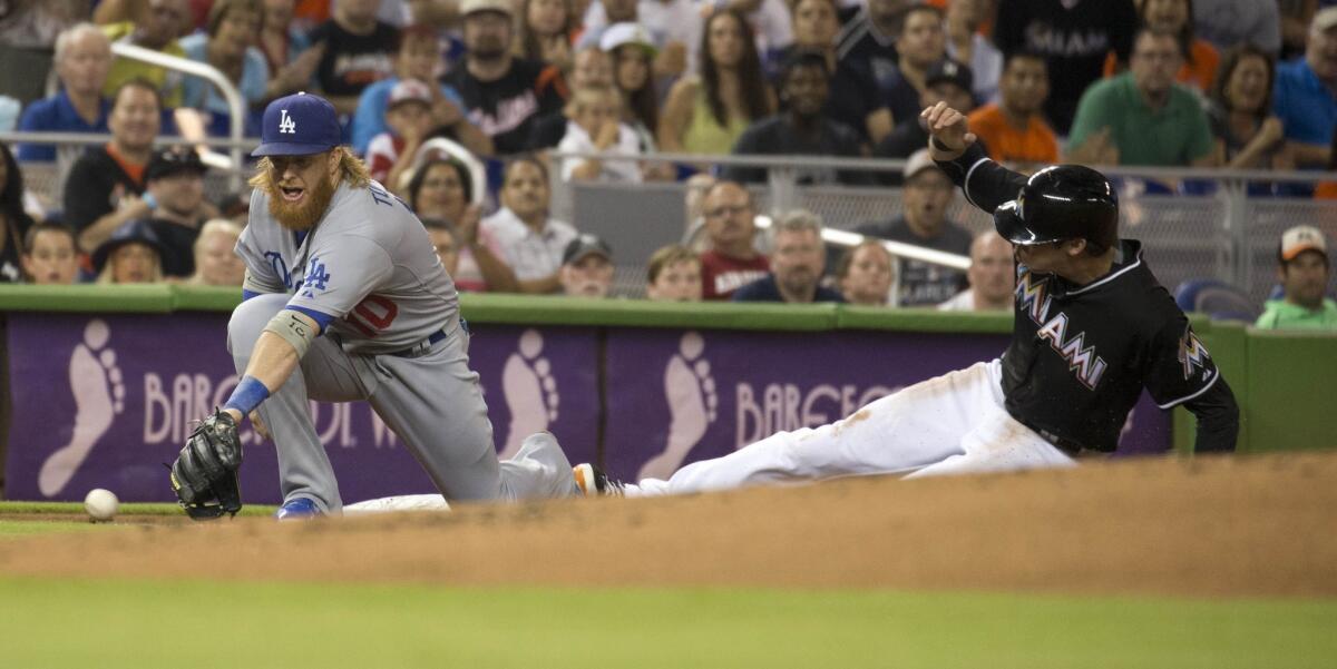 Dodgers third baseman Justin Turner (misses the ball as Miami's Christian Yelich slides into third.