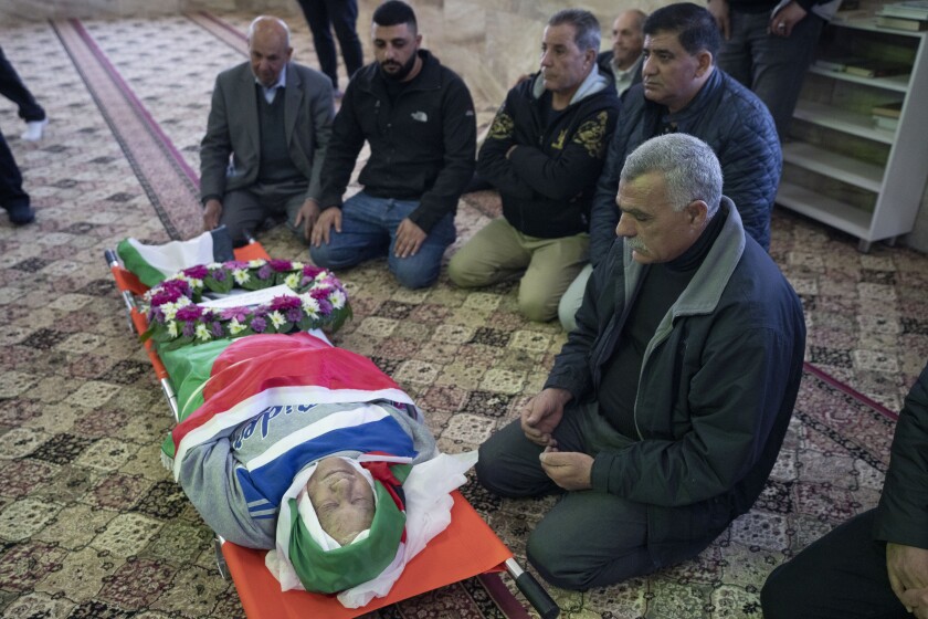 FILE - Mourners pray by the body of 78-year-old Omar Asaad, a Palestinian who has U.S. citizenship, during his funeral at a mosque, in the West Bank village of Jiljiliya, north of Ramallah, Jan. 13, 2022. An autopsy, undertaken by three Palestinian doctors, confirmed that Asaad, who was pronounced dead shortly after being detained by Israeli troops in the occupied West Bank, died of a heart attack caused by “external violence.” (AP Photo/Nasser Nasser, File)