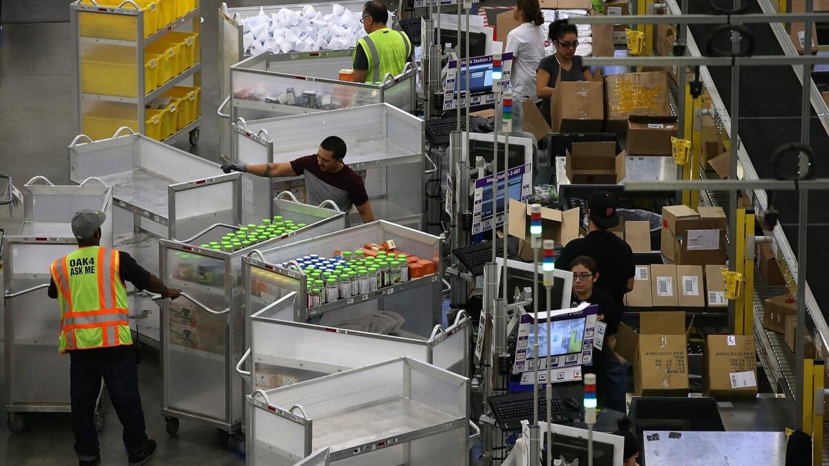 Amazon.com workers pack orders at an Amazon fulfillment center in Tracy, Calif. Amazon said it will boost its minimum pay for all U.S. workers to $15 an hour.