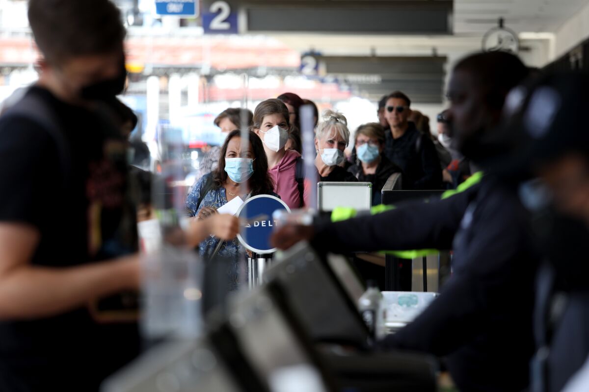 Airport passengers wearing face masks in line at an airport.