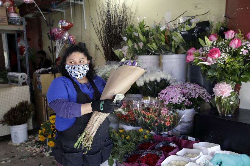 Evelyn Linares sells flowers at the Los Angeles Flower Market Wednesday, May 6, 2020, in Los Angeles. Los Angeles Mayor Eric Garcetti on Tuesday said he would allow wholesale florists to open as a horticultural exemption for the upcoming Mother's Day.