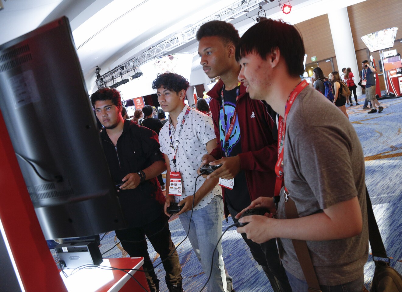 Small groups of friends demo the new Super Smash Bros Ultimate video game at Comic-Con 2018 in San Diego.