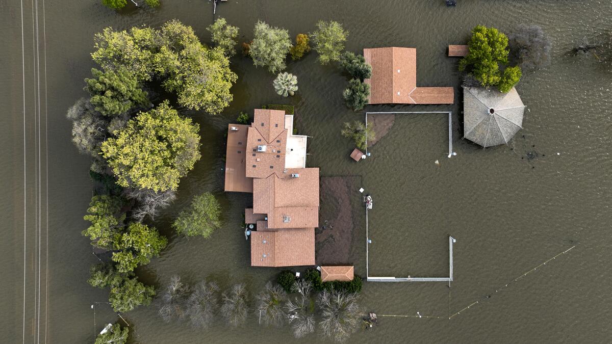 A bird's-eye view of a flooded home surrounded by muddy water.