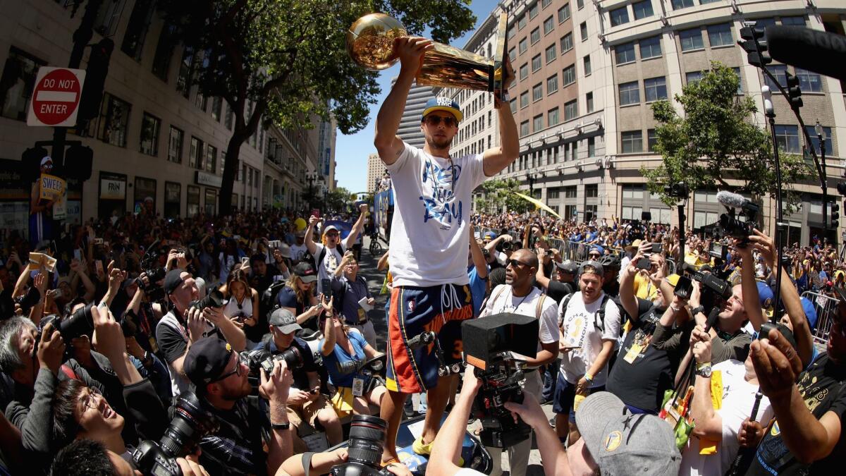 Stephen Curry raises championship trophy for fans.