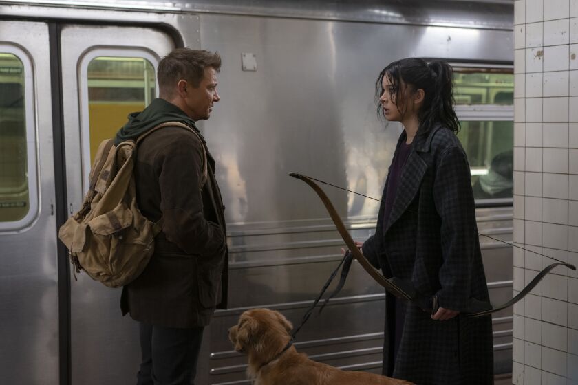 a man, a woman holding a bow and a dog near a train