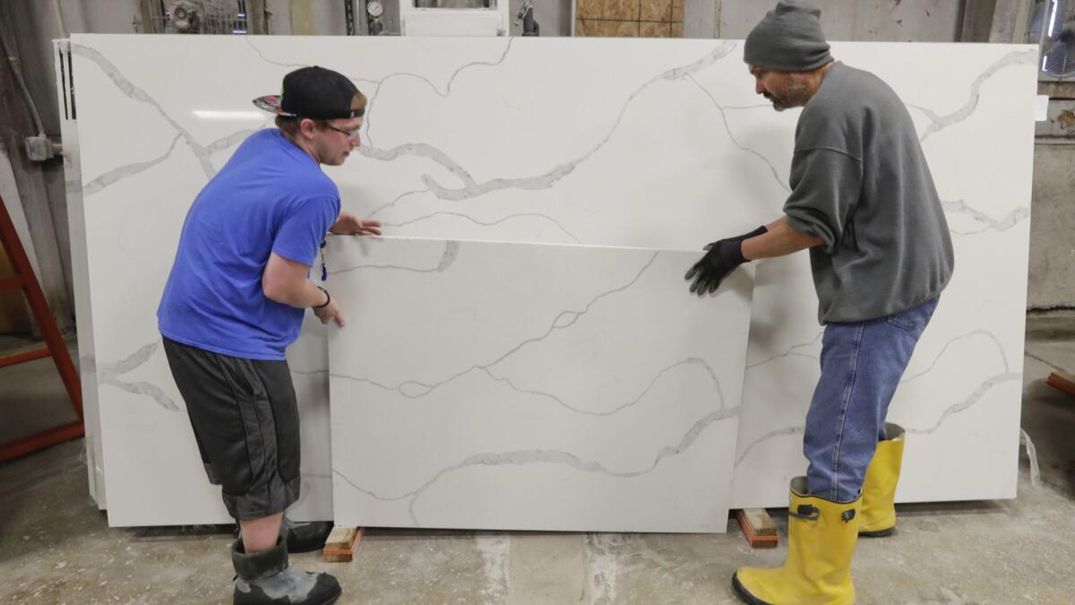 Workers move imported quartz slabs from China in the warehouse at Marble Uniques in Tipton, Ind., on May 3.