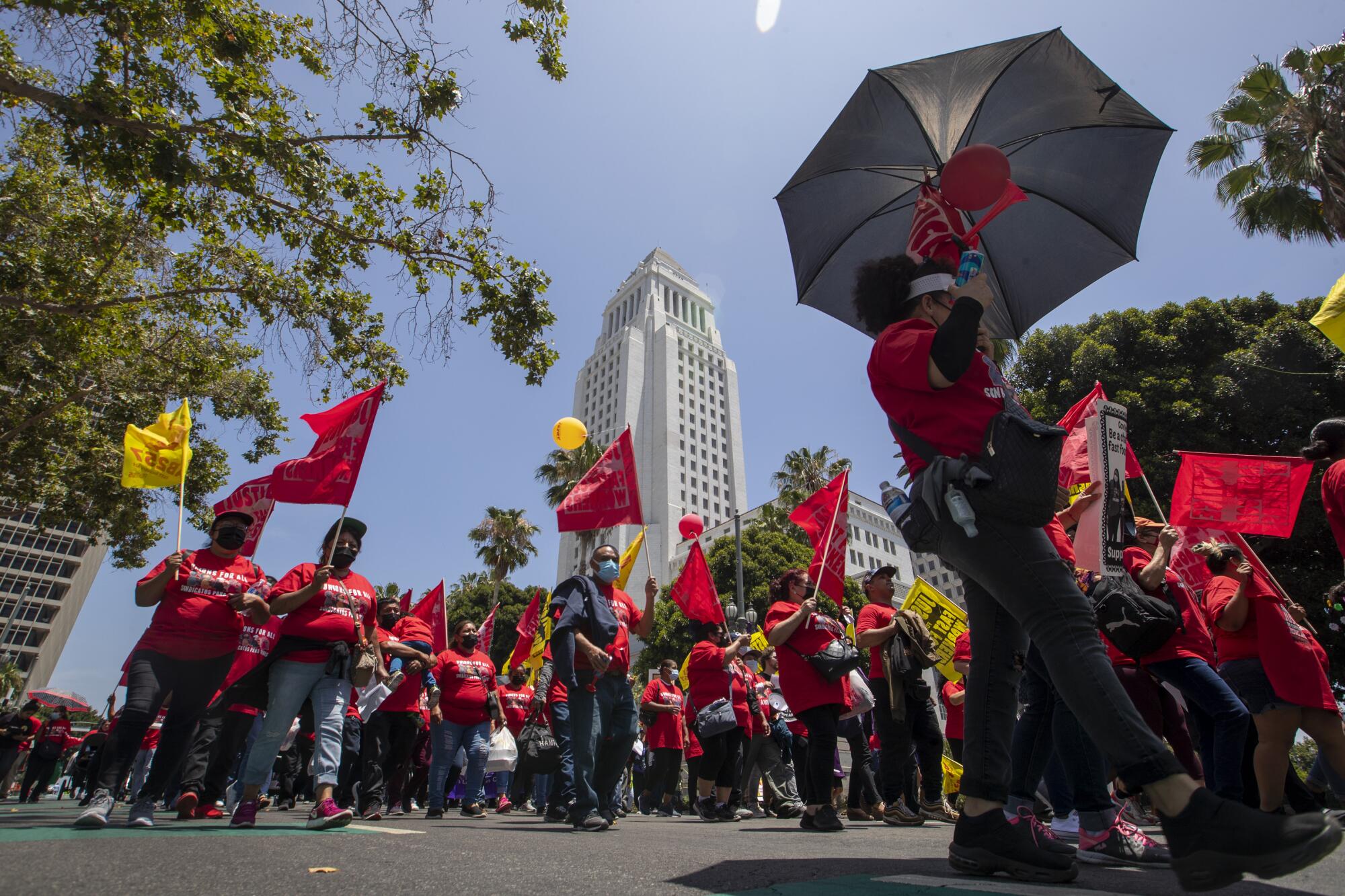 People carrying red and yellow flags demonstrate in front of Los Angeles City Hall.
