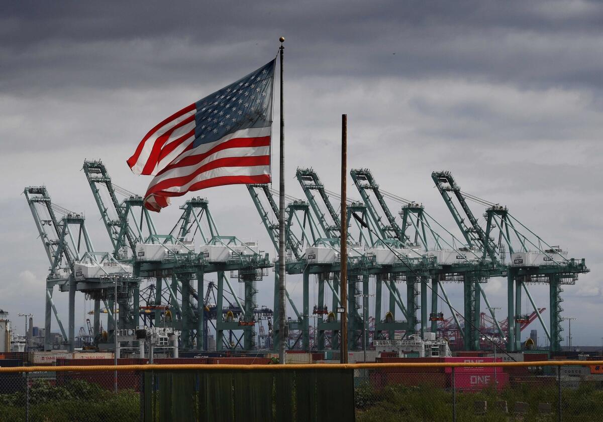 The U.S. flag flies over shipping cranes and containers at the Port of Long Beach.