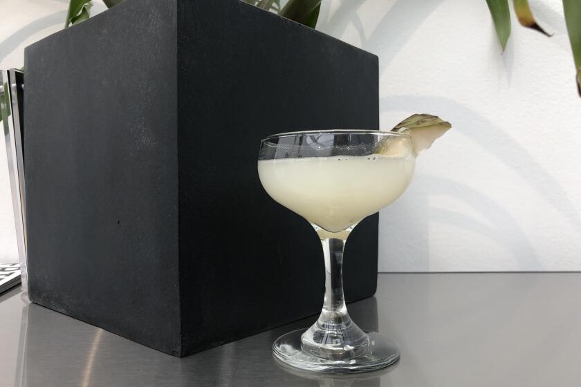 A photo of a cocktail with a piece of chirimoya fruit wedged on the rim.