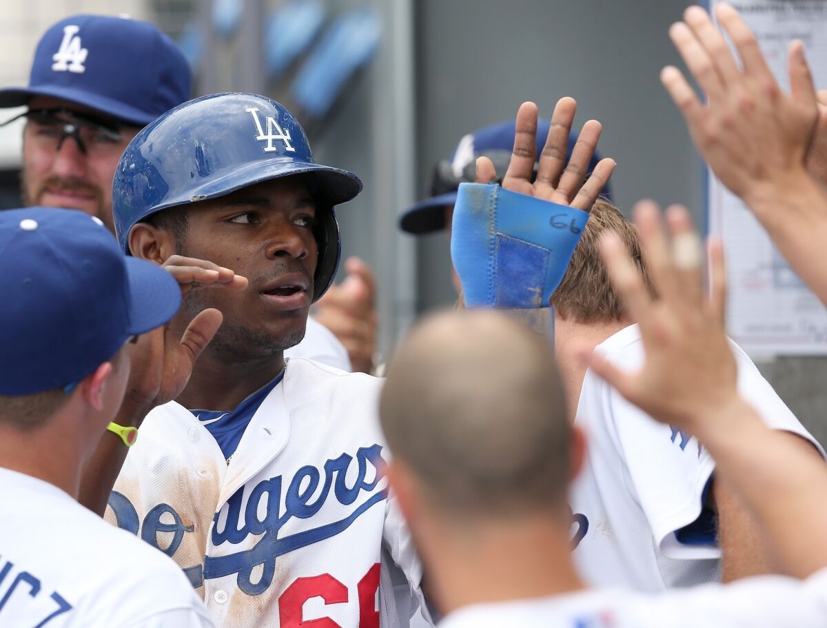 Dodgers outfielder Yasiel Puig is congratulated by his teammates after scoring a run during the fourth inning of the Dodgers' 6-1 victory over the Philadelphia Phillies on Sunday.