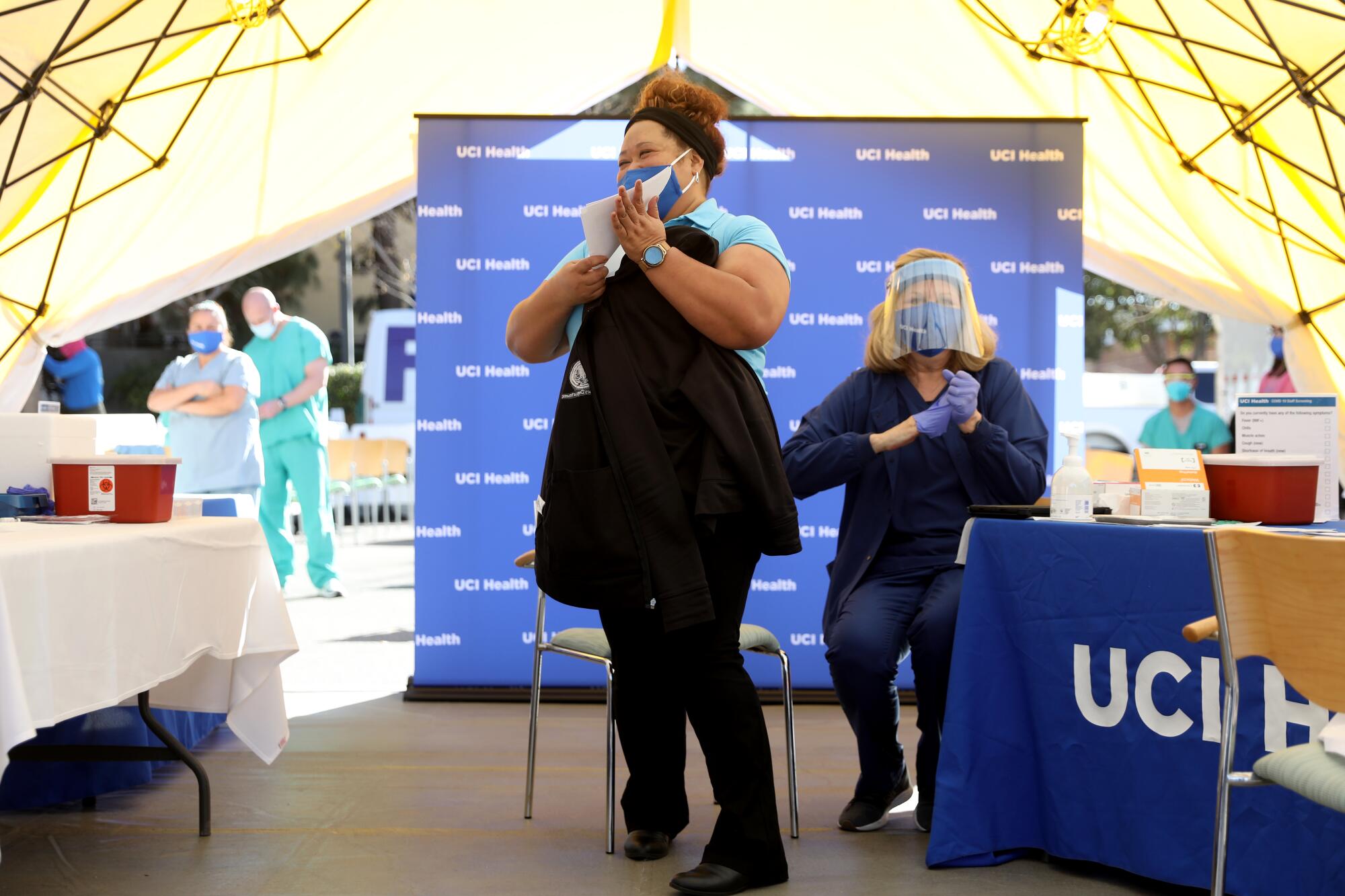 Katalina Vakalahi, center, UCI Health emergency department worker, receives a Pfizer BioNTech COVID-19 vaccine.