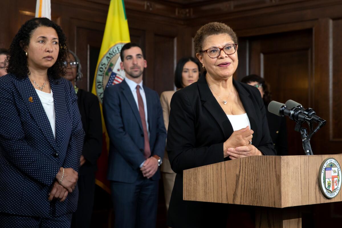 Los Angeles Mayor Karen Bass, accompanied with her team, speaks from behind a lectern.