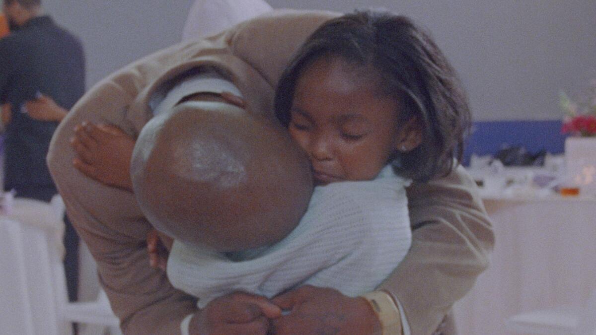 A man hugs his young daughter.