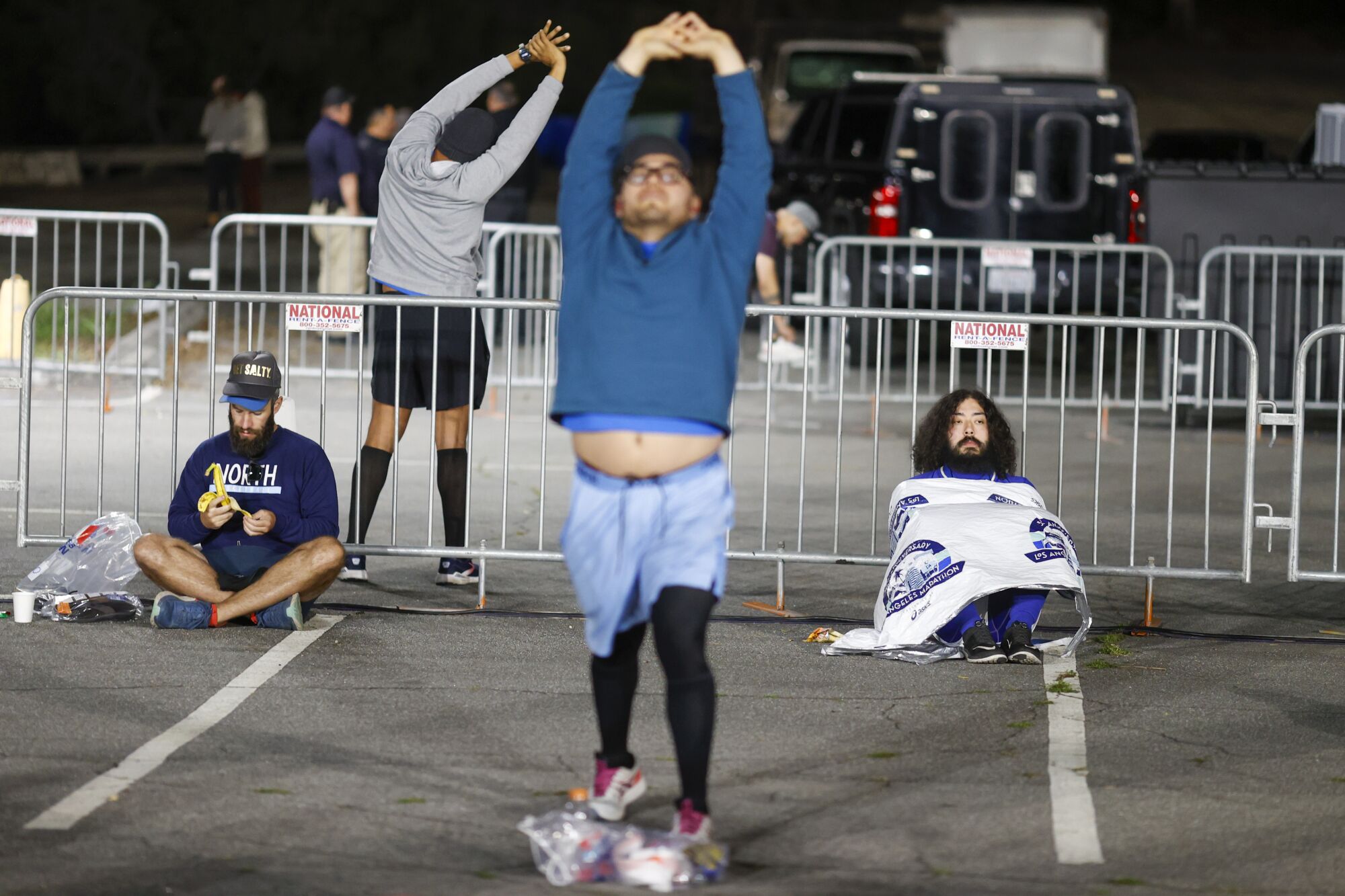 Runners stretch and sit under blankets at Dodger Stadium.
