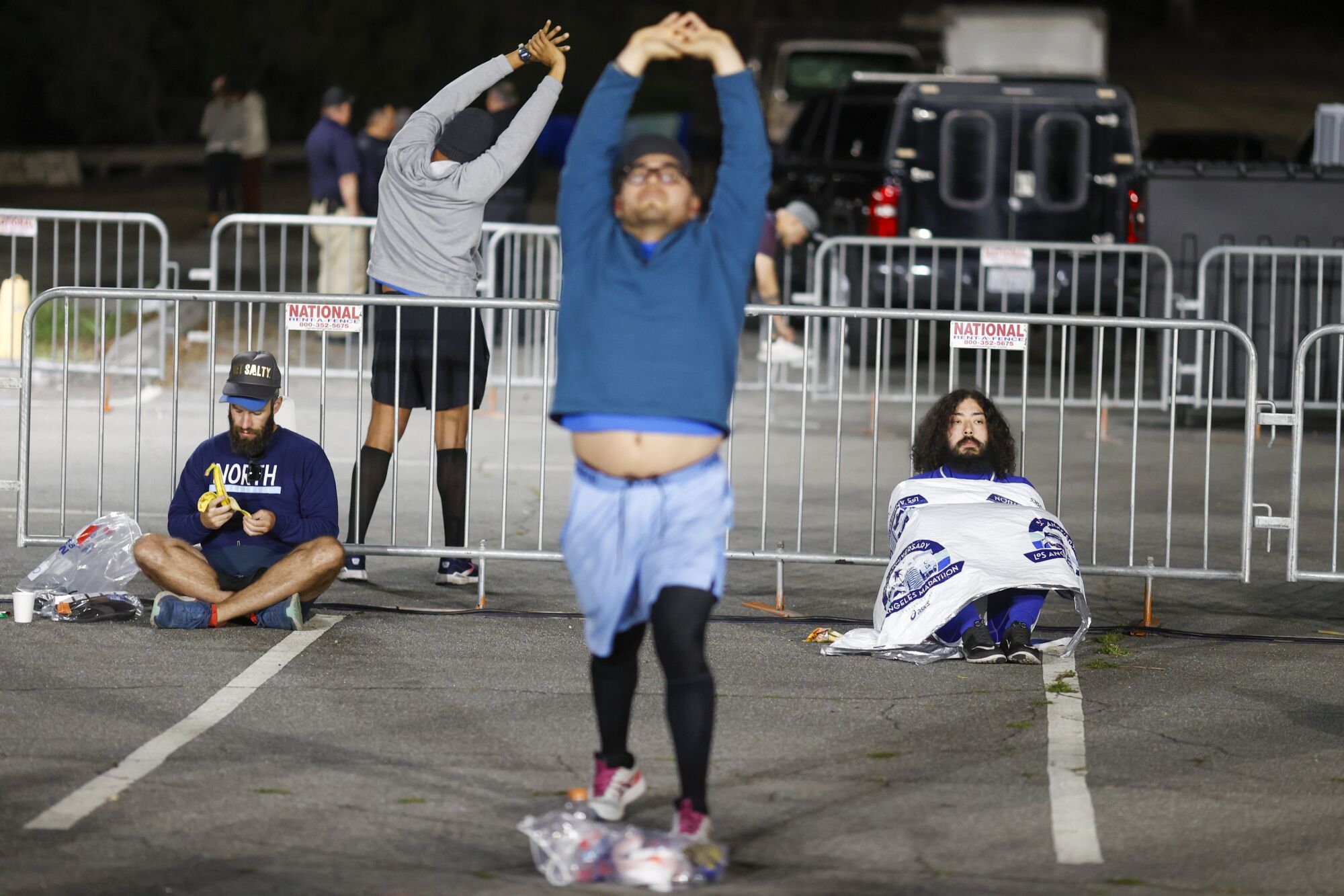 Undeterred by the weather, runners take to the streets for the 38th LA Marathon 2 Runners stretch and sit under blankets at Dodger Stadium.