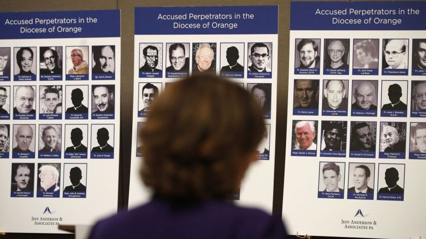 A survivor of sexual abuse looks at photos of Catholic clergy accused of sexual misconduct during a news conference in Orange on Dec. 8.