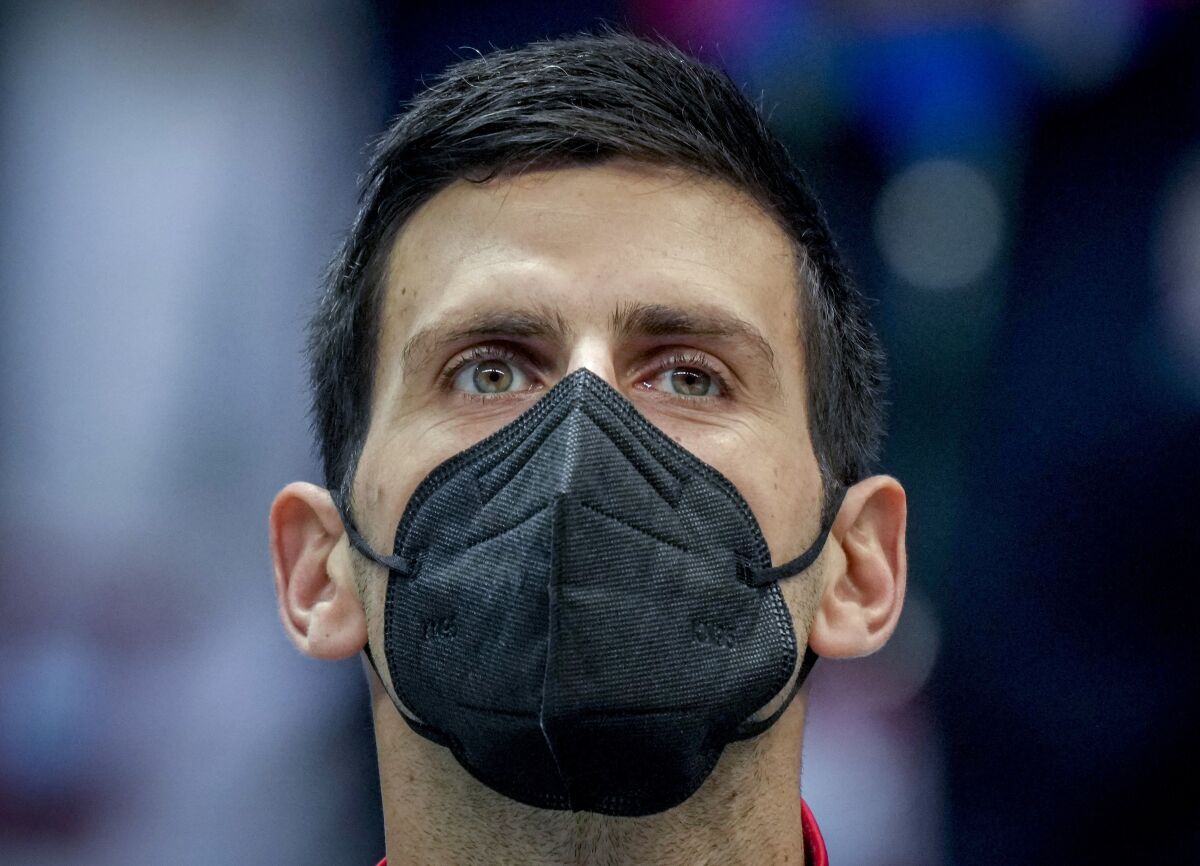 FILE - Serbia's Novak Djokovic wears a face mask as he listens to the national anthems prior to a Davis Cup group F match between Serbia and Austria in Innsbruck, Austria, Friday, Nov. 26, 2021. Novak Djokovic says he will not be able to compete at the upcoming tennis tournaments in Indian Wells, California, and Miami because he is unvaccinated and can’t travel to the United States, Wednesday, March 9, 2022.(Photo/Michael Probst, File)