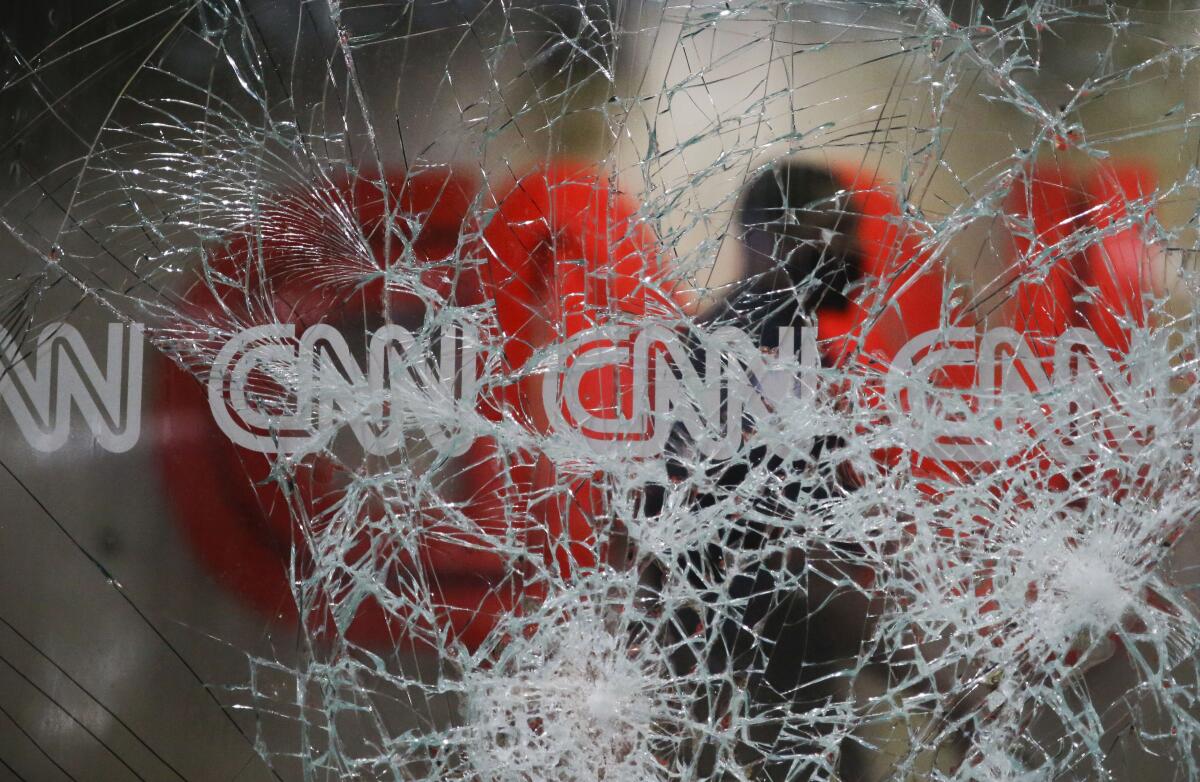 A security guard walks behind shattered glass at the CNN building in the aftermath of a demonstration against police violence.