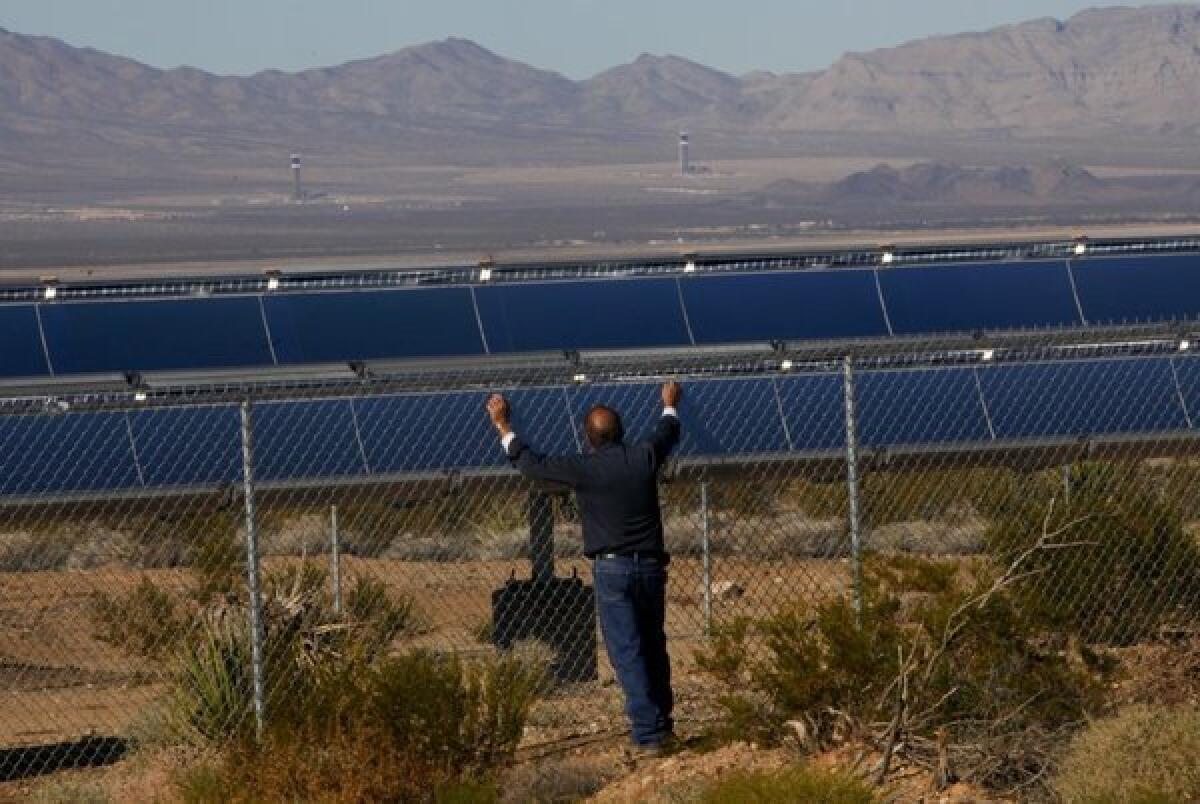 Ron Handley of Nipton, Calif., looks through the fence surrounding the Ivanpah solar thermal power plant.