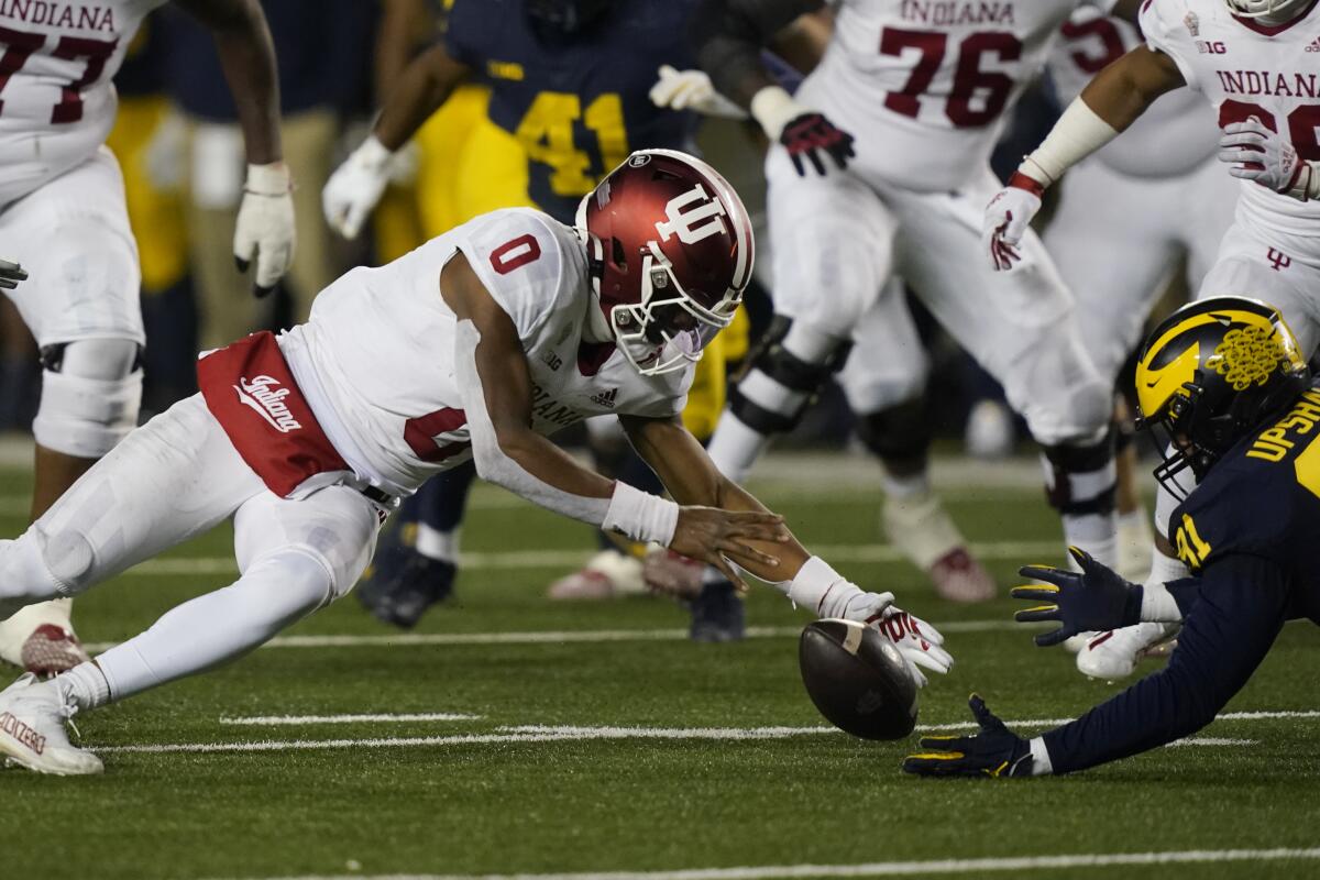 Indiana quarterback Donaven McCulley (0) and Michigan defensive end Taylor Upshaw (91) reach for the fumble during the second half of an NCAA college football game, Saturday, Nov. 6, 2021, in Ann Arbor, Mich. McCulley recovered the ball. (AP Photo/Carlos Osorio)