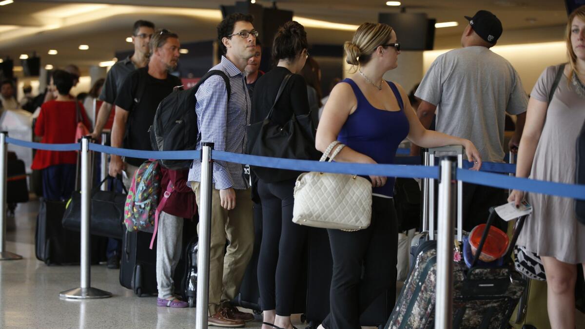 Travelers wait at the Delta Air Lines counter at Los Angeles International Airport on Sept. 4, 2015, the getaway day for the Labor Day holiday. Industry leaders predict 16.5 million people will travel on U.S. carriers this holiday weekend.