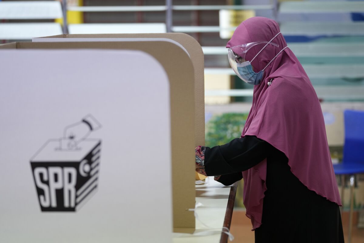 FILE - A woman casts her vote during a state election at a voting center in Malacca, Malaysia, Saturday, Nov. 20, 2021. Malaysian Prime Minister Ismail Sabri's Malay party has defeated its allies in the ruling party and the opposition to score a landslide victory in a second state election that could presage early national polls. (AP Photo/Vincent Thian, File)