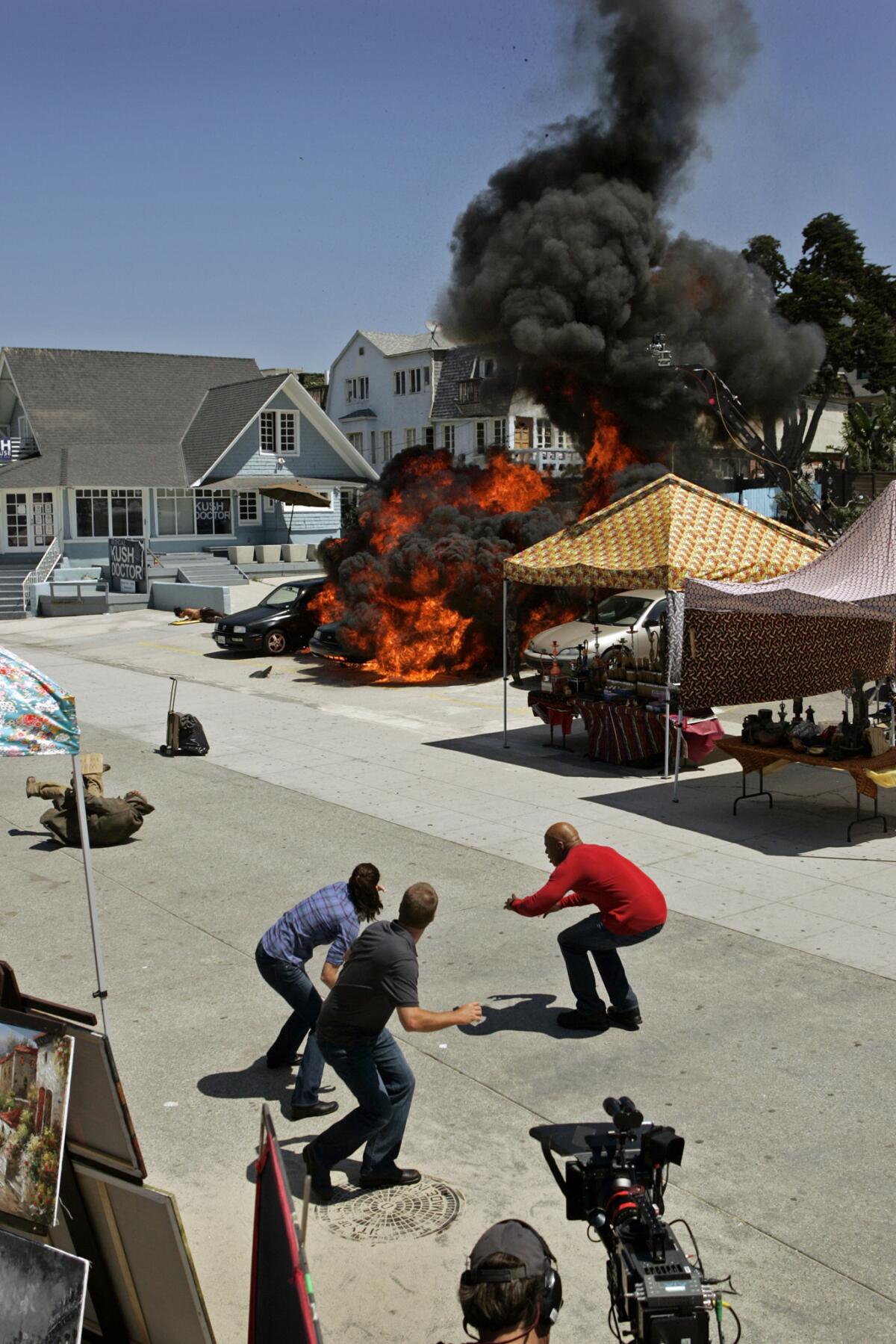 Actors Daniela Ruah, left, Chris O'Donnell and LL Cool J react as a car is exploded on Ocean Front Walk in Venice during shooting of "NCIS: Los Angeles" in 2010.