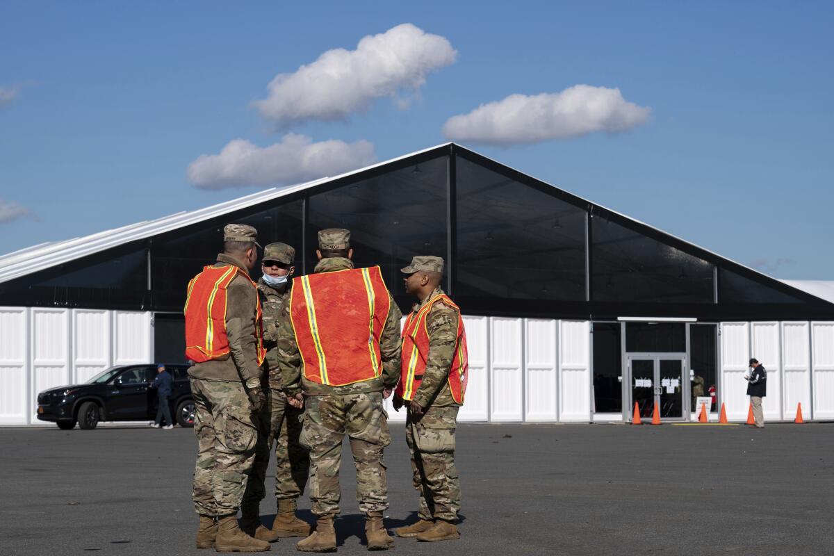 National Guard members stand outside a large structure.