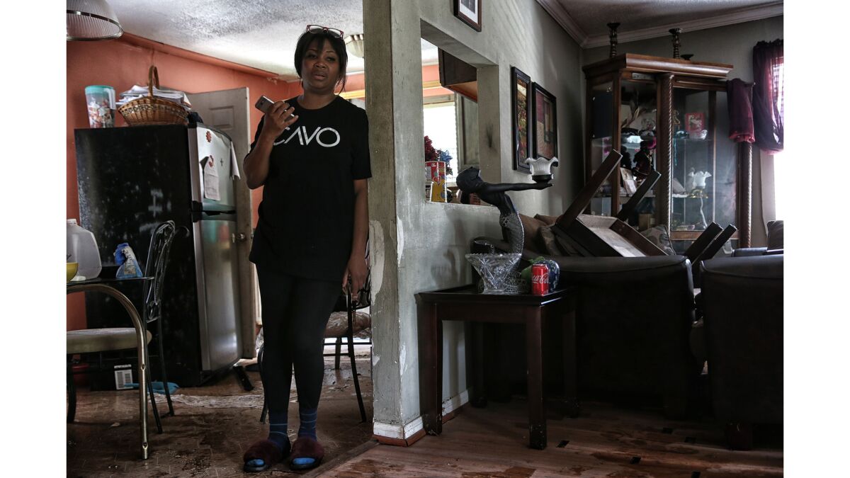 A day after flood waters receded, Yvonne Feruson-Smith assesses the damage to her home while talking with her husband, Rico Smith.