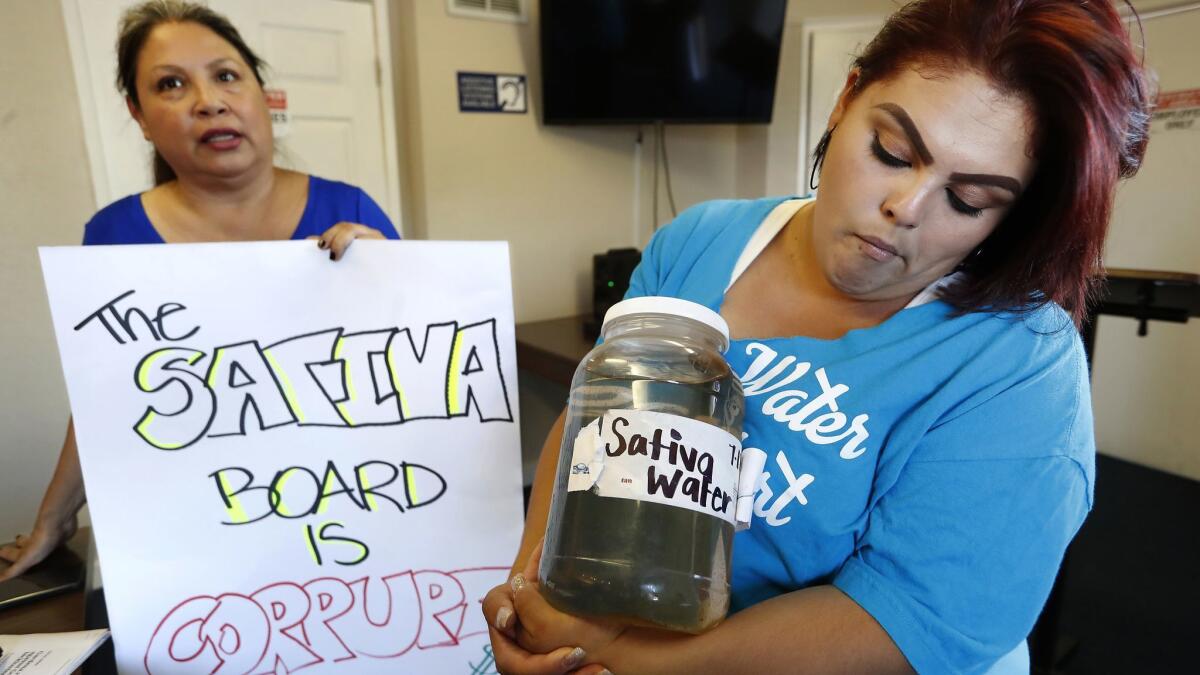 Compton resident Genoveva Camargo, right, holds water from her tap with activist Maria Estrada. They both support Assembly BIll 1577, which would dismantle the Sativa Los Angeles County Water District's board of directors.