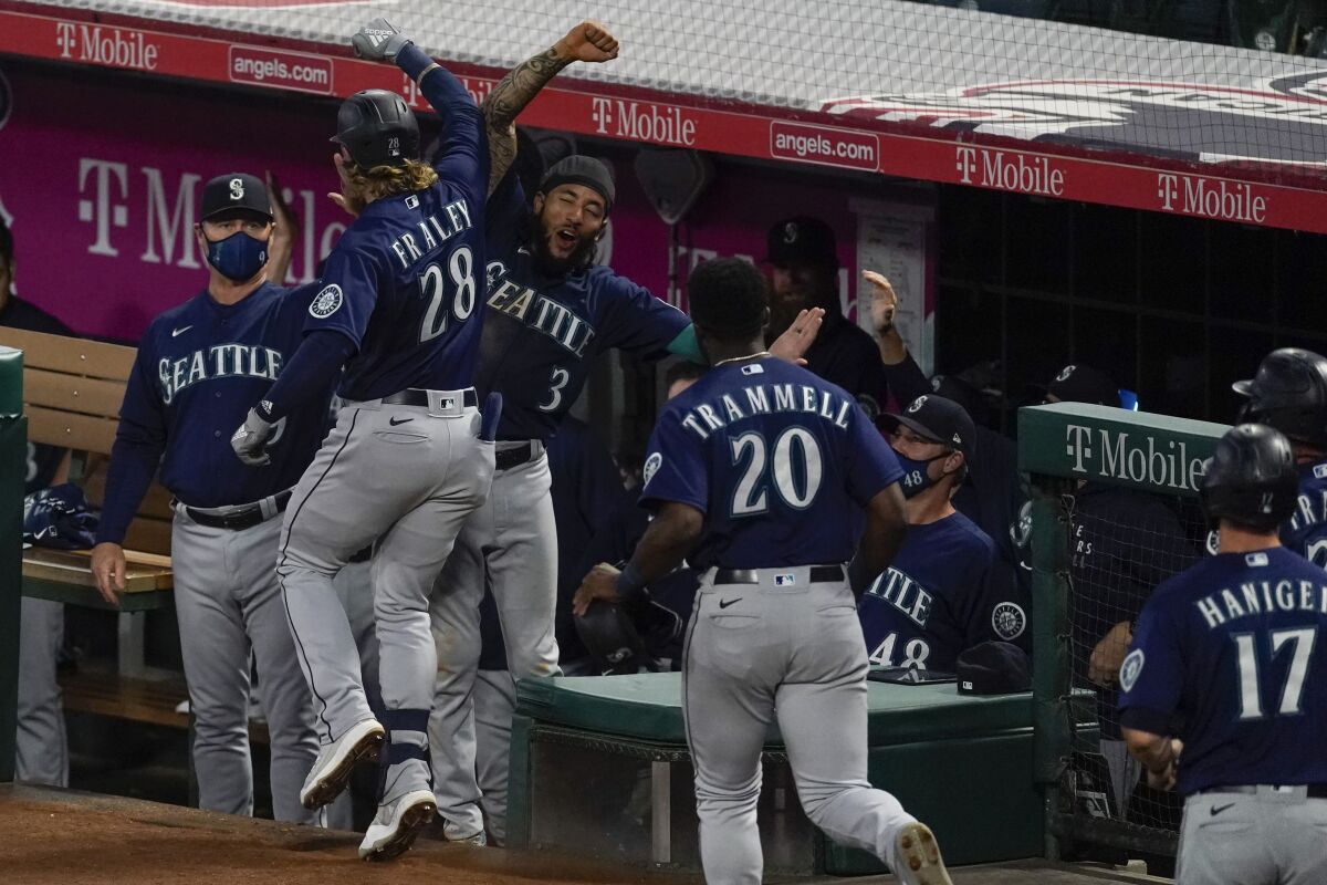 Seattle Mariners designated hitter Jake Fraley (28) celebrates with J.P. Crawford (3) after hitting a grand slam home run during the fourth inning of a baseball game against the Los Angeles Angels Saturday, June 5, 2021, in Anaheim, Calif. Mitch Haniger, Ty France, and Taylor Trammell also scored. (AP Photo/Ashley Landis)