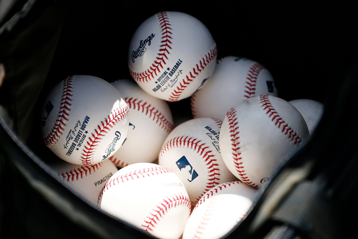 Baseballs sit in a bucket.