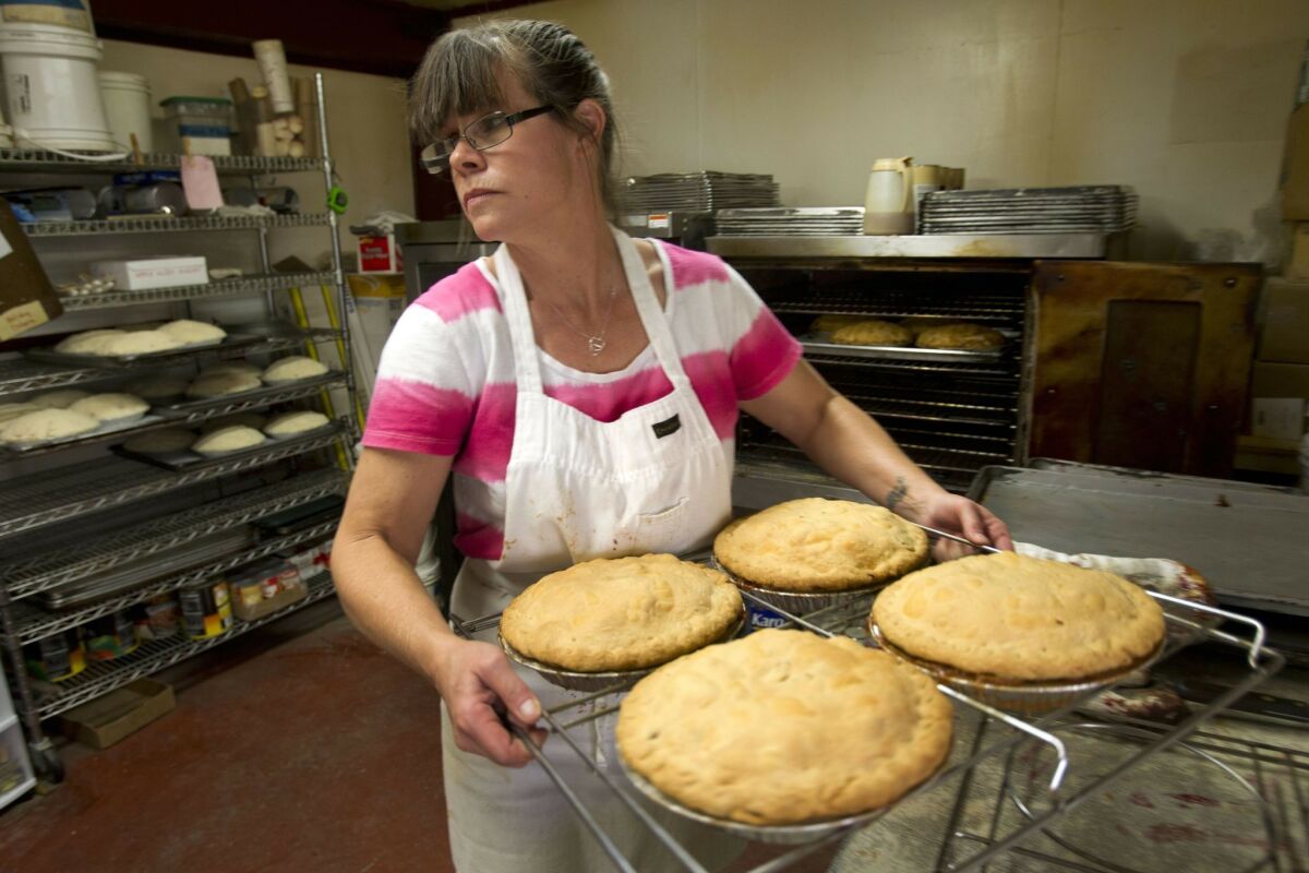 Vicki Newman moves a rack of traditional apple pies that are fresh out of the oven at Apple Alley Bakery in Julian in 2012.