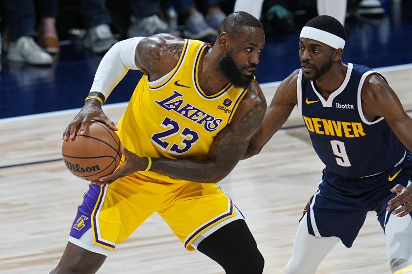 Los Angeles Lakers forward LeBron James, left, looks to pass the ball as Denver Nuggets.