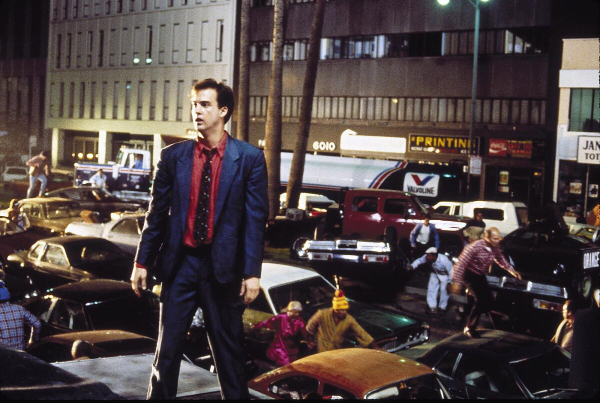 A man stands atop a truck as Mid-Wilshire Los Angeles descends into chaos.