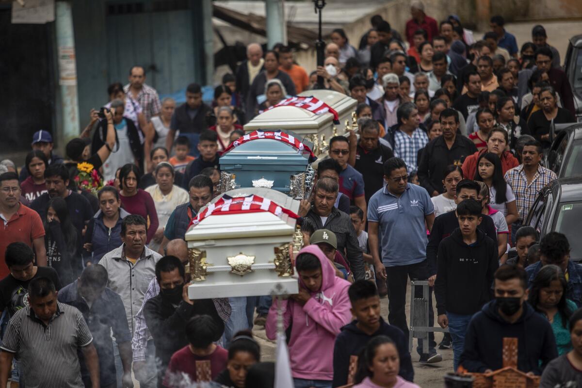 Three caskets are carried in a street funeral procession. 